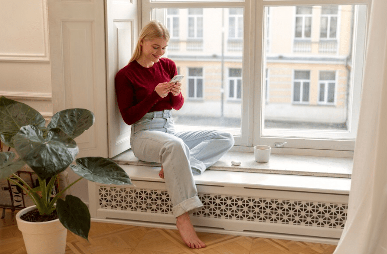 Picture of a woman sitting over her electric baseboard heater.
