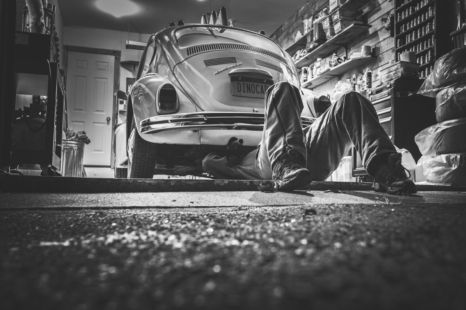 A person working on the underside of a car in a heated garage. A person working on the underside of a car in a heated garage.