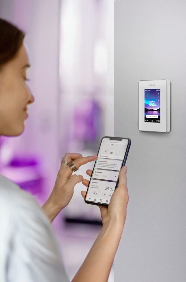 Woman using the MyHeating App on her phone to manage the 7iE Thermostat.