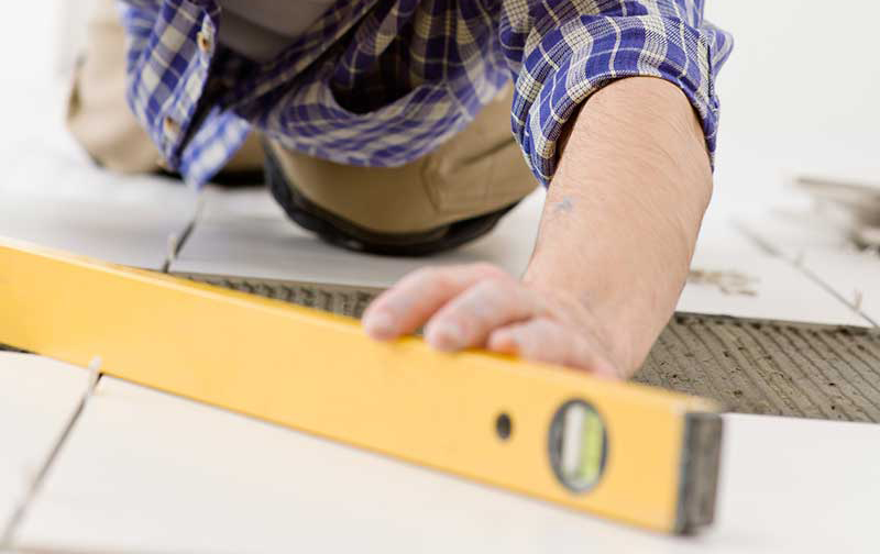 man using level on tiling