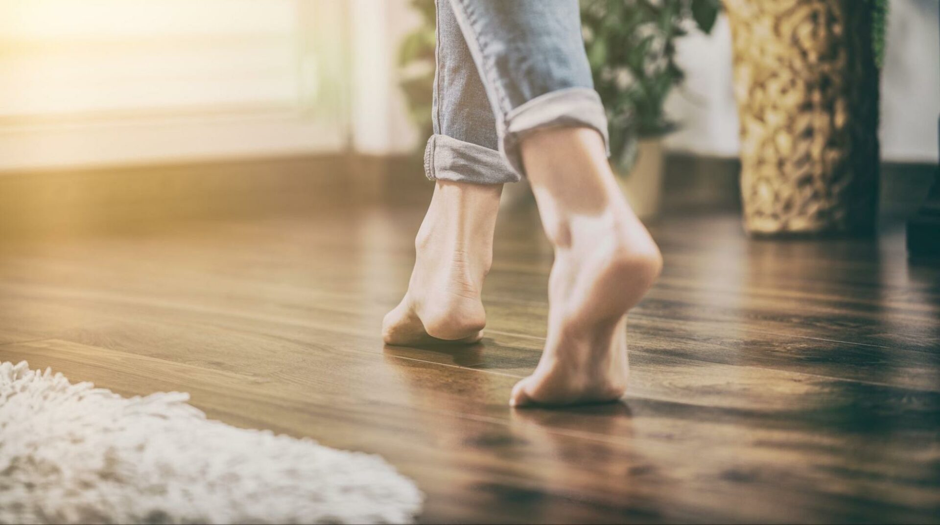 A person walking on a wood floor heated by electric radiant heating cables.