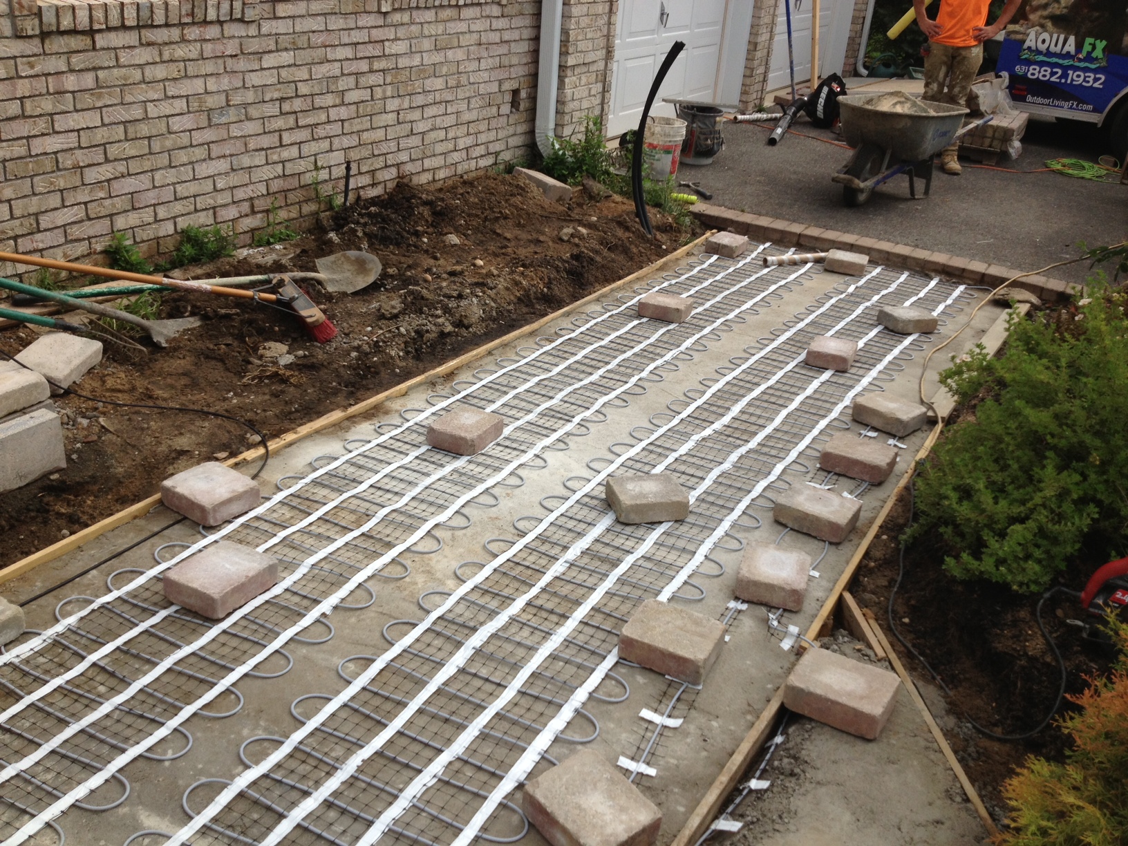 installer laying down snow melting cable mat on driveway