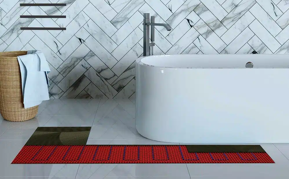 A cutaway in a tiled bathroom floor showing Warmup's DCM-PRO Radiant Heat system underneath.