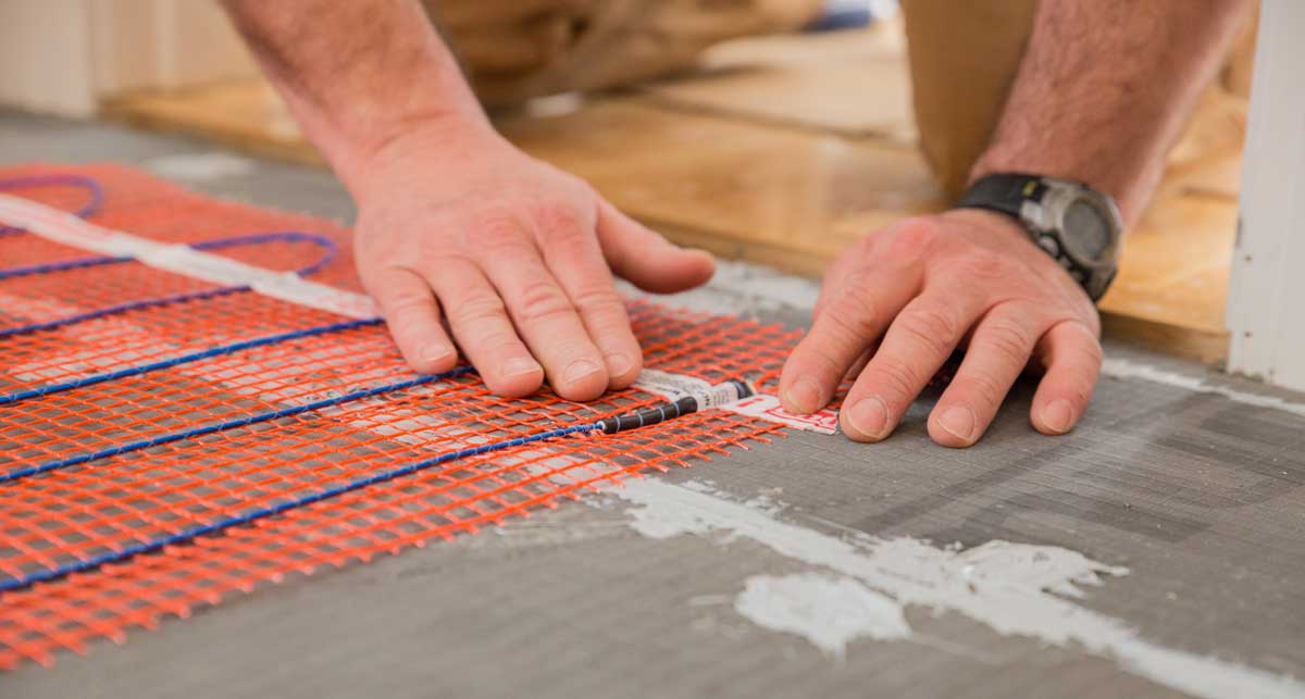 A man installing Warmup's StickyMat Underfloor Radiant Heating Mat.